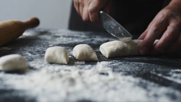 Mâinile femeilor taie aluatul în bucăți cu cuțit de bucătărie — Videoclip de stoc