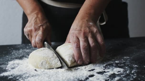 Женские руки режут тесто на куски кухонным ножом — стоковое видео