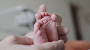 Genç Anne yavaşça onun yeni doğan bebek bacaklarını okşayarak