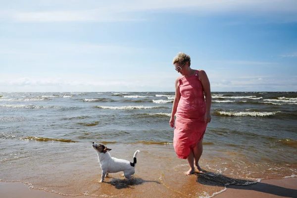 Жінка і собака стоять у морі — стокове фото