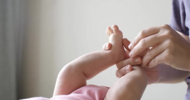 Yeni doğan bebeğinin ayak masajı yapıyor anne