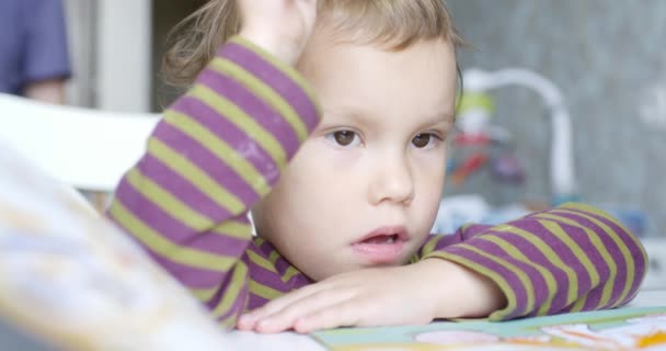 Niño con una cara melancólica que dibuja en el álbum — Vídeos de Stock