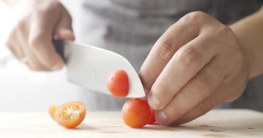 Cook ince ahşap tahta üzerinde kiraz domates doğrayın