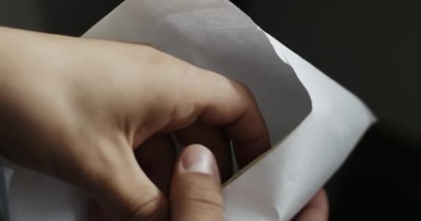 Человек смотрит в конверт, который представляет собой пакет 100 долларов купюр — стоковое видео