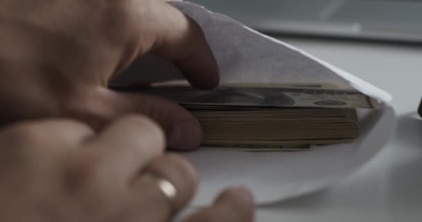 男人看着信封, 这是包的100美元钞票 — 图库视频影像