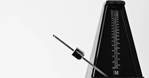 Крупним планом зображення старовинного метронома з маятником б'є повільний ритм на сірому фоні — стокове відео