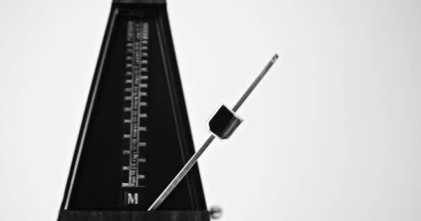 Close-up shot van vintage metronoom met slinger slaat traag ritme op de grijze achtergrond — Stockvideo