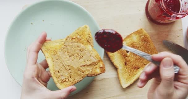 Person machen ein Sandwich mit Erdnussbutter und Himbeermarmelade — Stockvideo