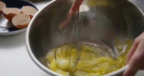 Osoba přípravě domácí omeleta míchání vejce s rukou corolla. — Stock video