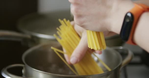 Pone espaguetis de pasta en una olla de agua hirviendo — Vídeo de stock