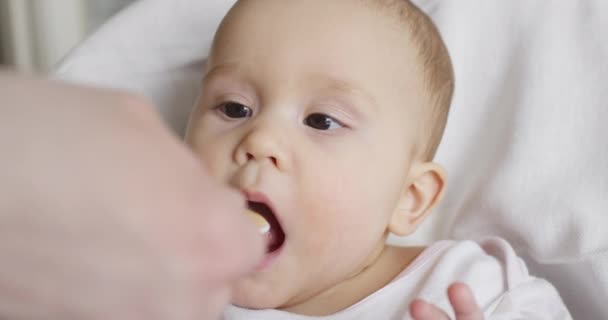 Mom feeds her little 8 months old baby from a spoon — Stock Video