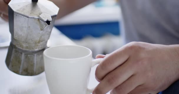 Coup de culture de la personne versant du café dans la tasse de la cafetière geyser . — Video