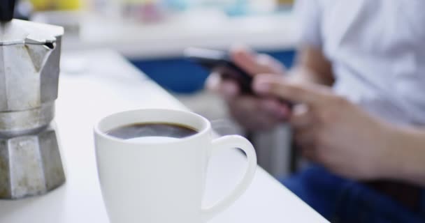 Adam smartphone ile masada oturur ve taze sıcak içecek içecekler — Stok video