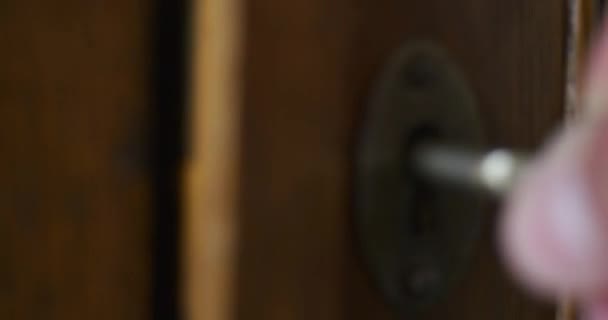 Человек вручную поворачивает старый ключ в замочной скважины старинного деревянного шкафа — стоковое видео