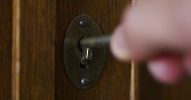 Personne à la main tourne vieille clé dans le trou de serrure de l'armoire en bois antique — Video