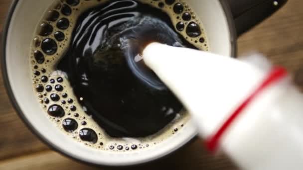 Verter leche corriente de la botella a la taza de americano — Vídeo de stock