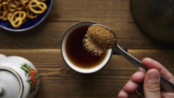 Pour cane sugar from spoon into cup of tea — Stock Video