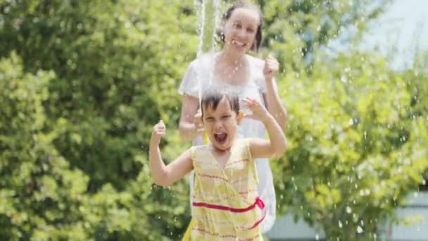 Klein meisje dansen onder de spray van een tuinslang — Stockvideo