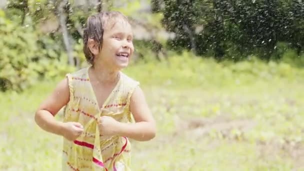 Kleines Mädchen tanzt unter der Gischt aus einem Gartenschlauch — Stockvideo