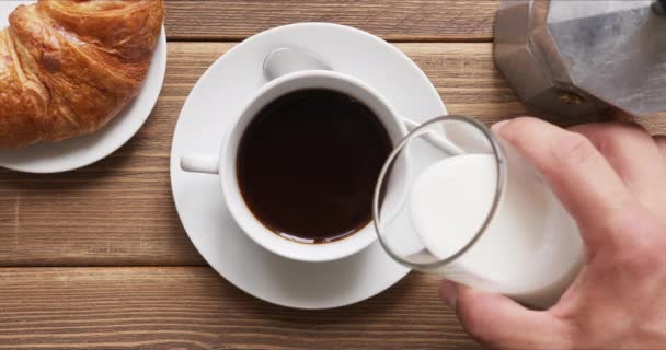 Person gießt Milch in schwarzen Morgenkaffee. — Stockvideo