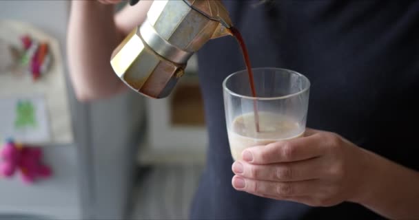 Frau gießt frisch gebrühten heißen Kaffee aus Moka-Kaffeemaschine in Becher mit Milch zum Frühstück — Stockvideo