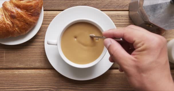 Человек смешивает сахар в кофе с молоком с ложкой — стоковое видео