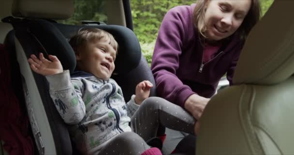 Woman fastening safety seat belt of baby sitting — Stock Video