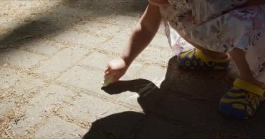 Parkta yere boya kalemleriyle resim yapan bir kız.