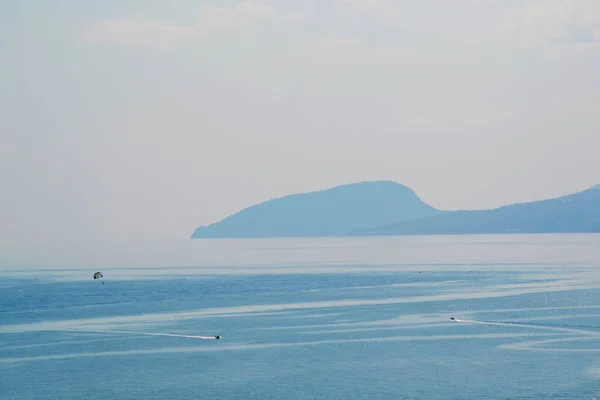 Human is traveling by parachute in the Black sea, Crimea on Mountings background in summer