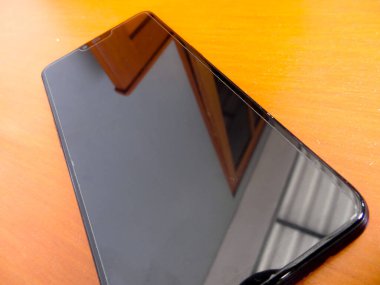 Kahverengi arka planda siyah akıllı telefon