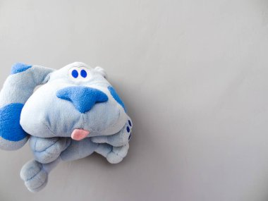 Gri arka planda mavi köpek şekilli oyuncak bebek