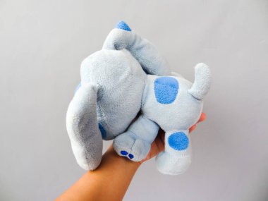 Gri arka planda mavi köpek şekilli oyuncak bebek