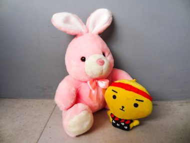 Pembe tavşan şeklinde bir bebek ve gri arka planda arkadaşı.