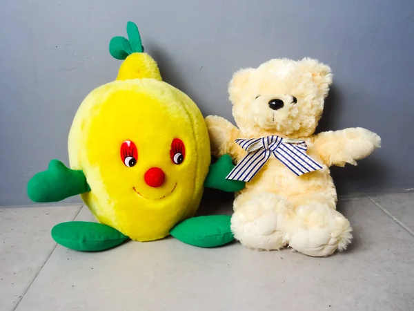 Uma Boneca Forma Fruta Amarela Sua Amiga Fundo Cinza — Fotografia de Stock