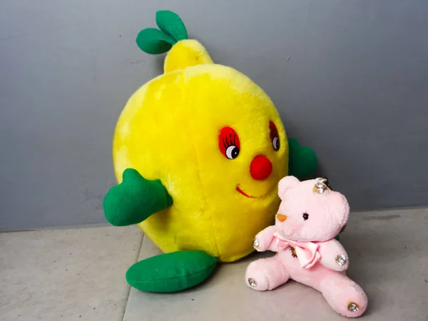 灰色の背景に黄色い果実型の人形と彼女の友人がいて — ストック写真