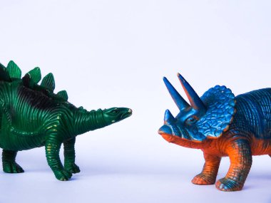 Beyaz arka planda mavi ve yeşil dinozor oyuncakları
