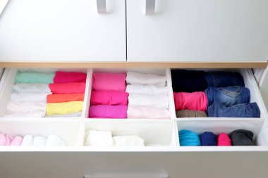 Çocuk odasında giysilerin dikey depolanması. Giysiler sürgüde dikey depolama için katlandı. Bir kızın dolabı..