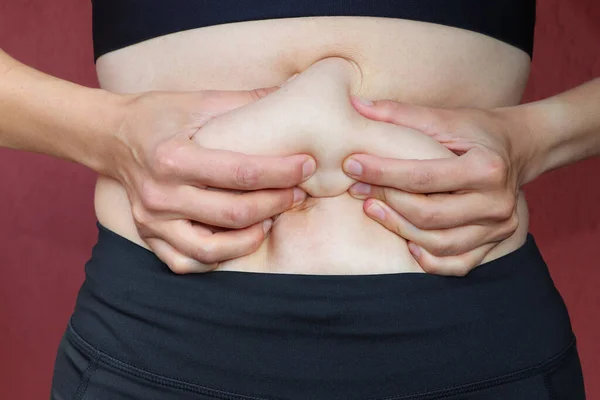 The hands clench fat belly. The belly after the birth of the child.