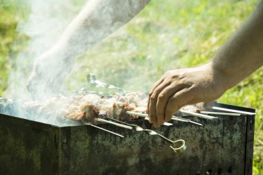 Barbekü ızgara yazları açık havada ellerini bile kavurma için şiş çevirmek.
