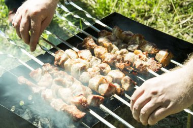 Barbekü ızgara yazları açık havada ellerini bile kavurma için şiş çevirmek.