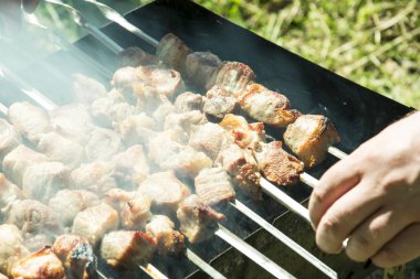 Barbekü ızgara yazları açık havada ellerini bile kavurma için şiş çevirmek.