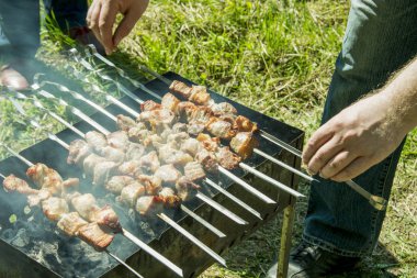 Barbekü ızgara yazları açık havada ellerini bile kavurma için şiş çevirmek.