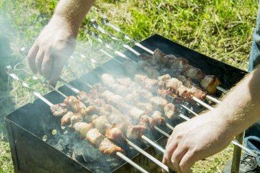Barbekü ızgara yazları açık havada ellerini bile kavurma için şiş çevirmek.