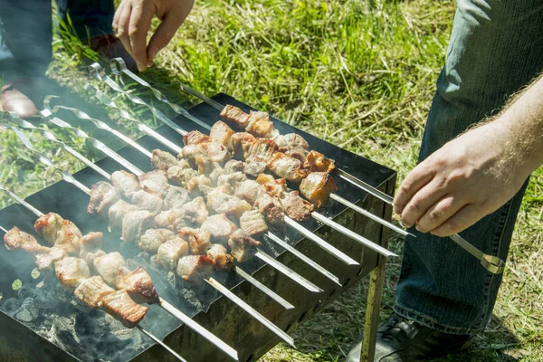 Barbekü ızgara yazları açık havada ellerini bile kavurma için şiş çevirmek.