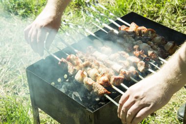 Barbekü ızgara yazları açık havada ellerini bile kavurma için şiş çevirmek.