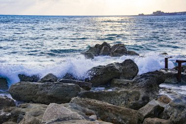 Gün batımından manzara modunda deniz suyu arasında kayalık plaj