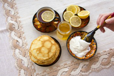 bir daire bir boyalı bardakta çay limon, krep, ekşi krema ve bir tahta kaşık overlaying için dilimlenmiş. rustik tarzı çay partisi