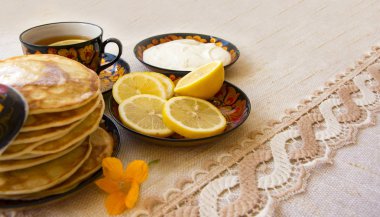 bir daire bir boyalı bardakta çay limon, krep, ekşi krema ve bir tahta kaşık overlaying için dilimlenmiş. rustik tarzı çay partisi