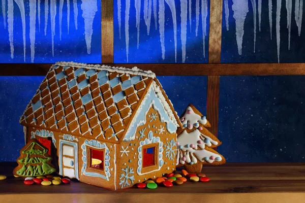 Gingerbread house on the background of the night window. Christmas gingerbread house. Night sky outside the window.