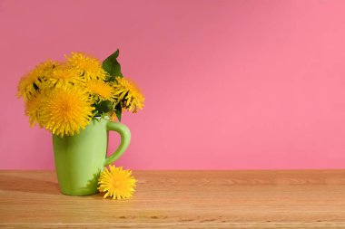 Karahindiba. Pembe bir arka plan üzerinde yeşil bir fincan çiçek bir buket. Metin için yer. Renk.